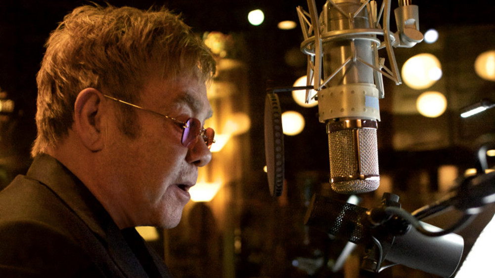 Elton John singt in ein Mikrofon